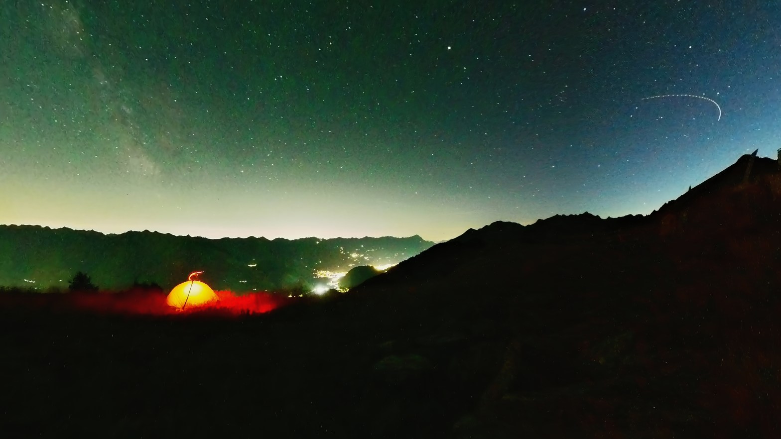 Orange beleuchtetes Zelt unter Sternen in den Bergen