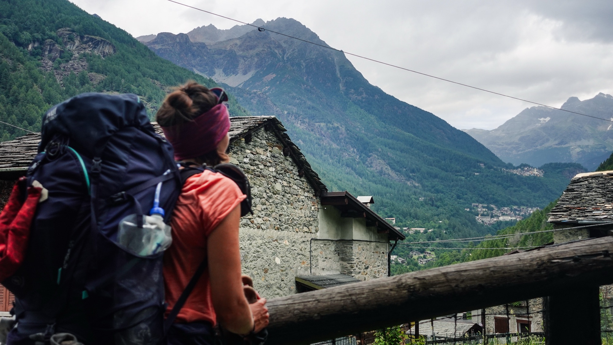 Wanderin blickt in Tal, daneben Berge